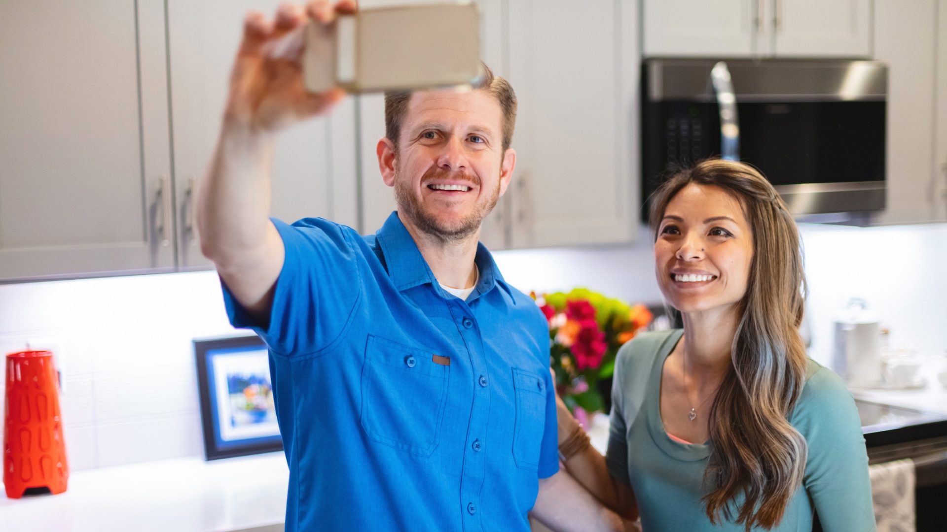 Homme et femme prenant une photo dans une cuisine